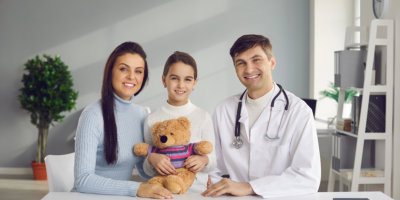 a pediatric patient with her mother and doctor taking a photo